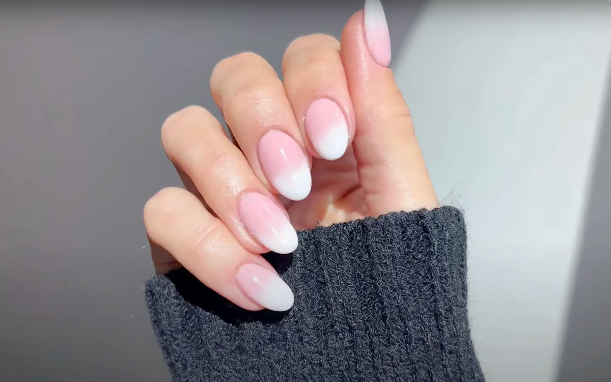 Hand met babyboom nagels in zachte roze wit ombre gemaakt met dipping powder techniek