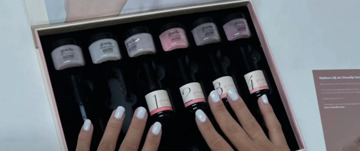 Een set van zes kleine cilindervormige nagellakflessen met zwarte doppen en roze accenten in een roségouden doos