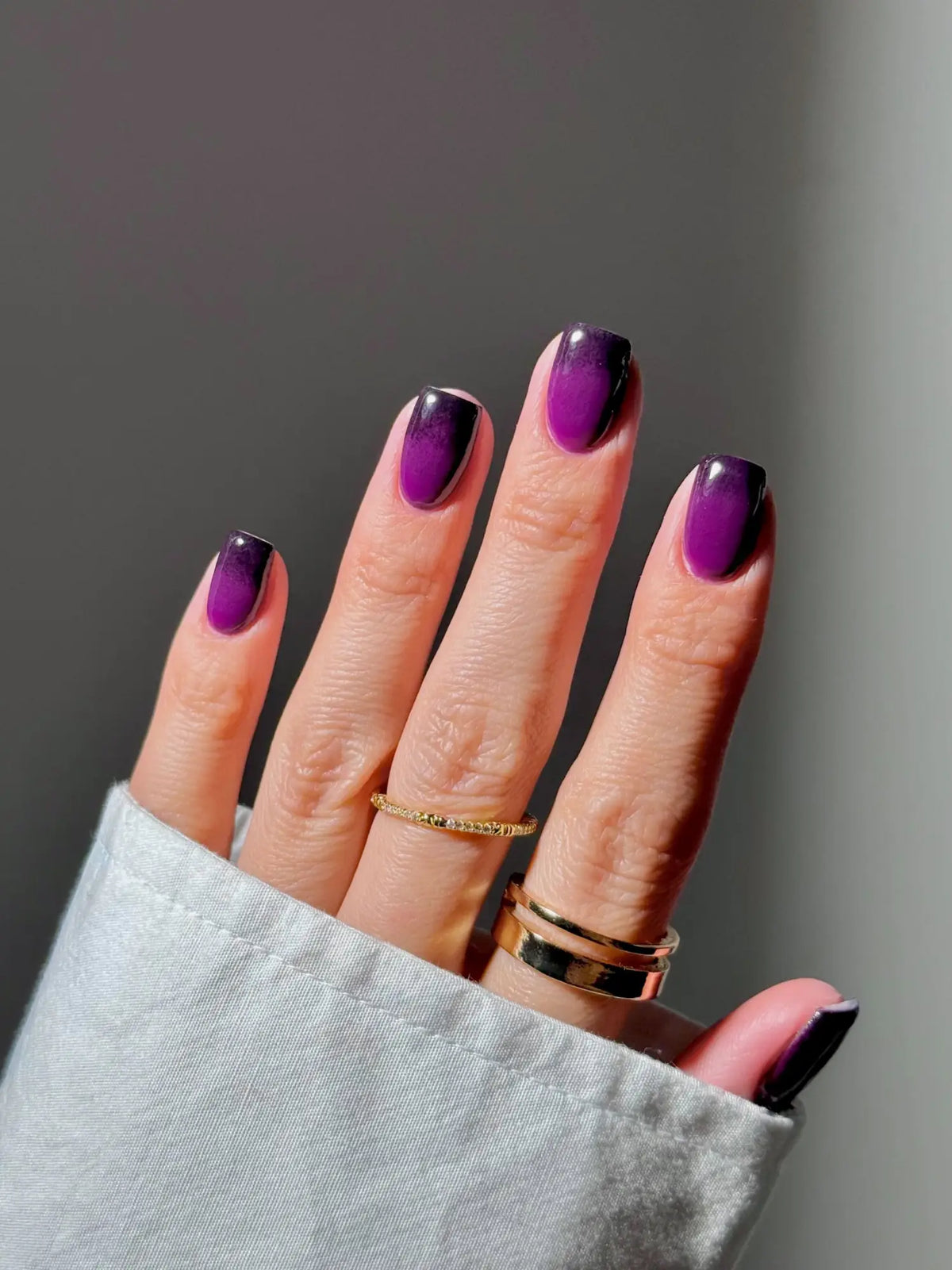 Paarse tot zwarte verlopende nagellak met een glanzende afwerking in een artikel over glowdip voor je nagels