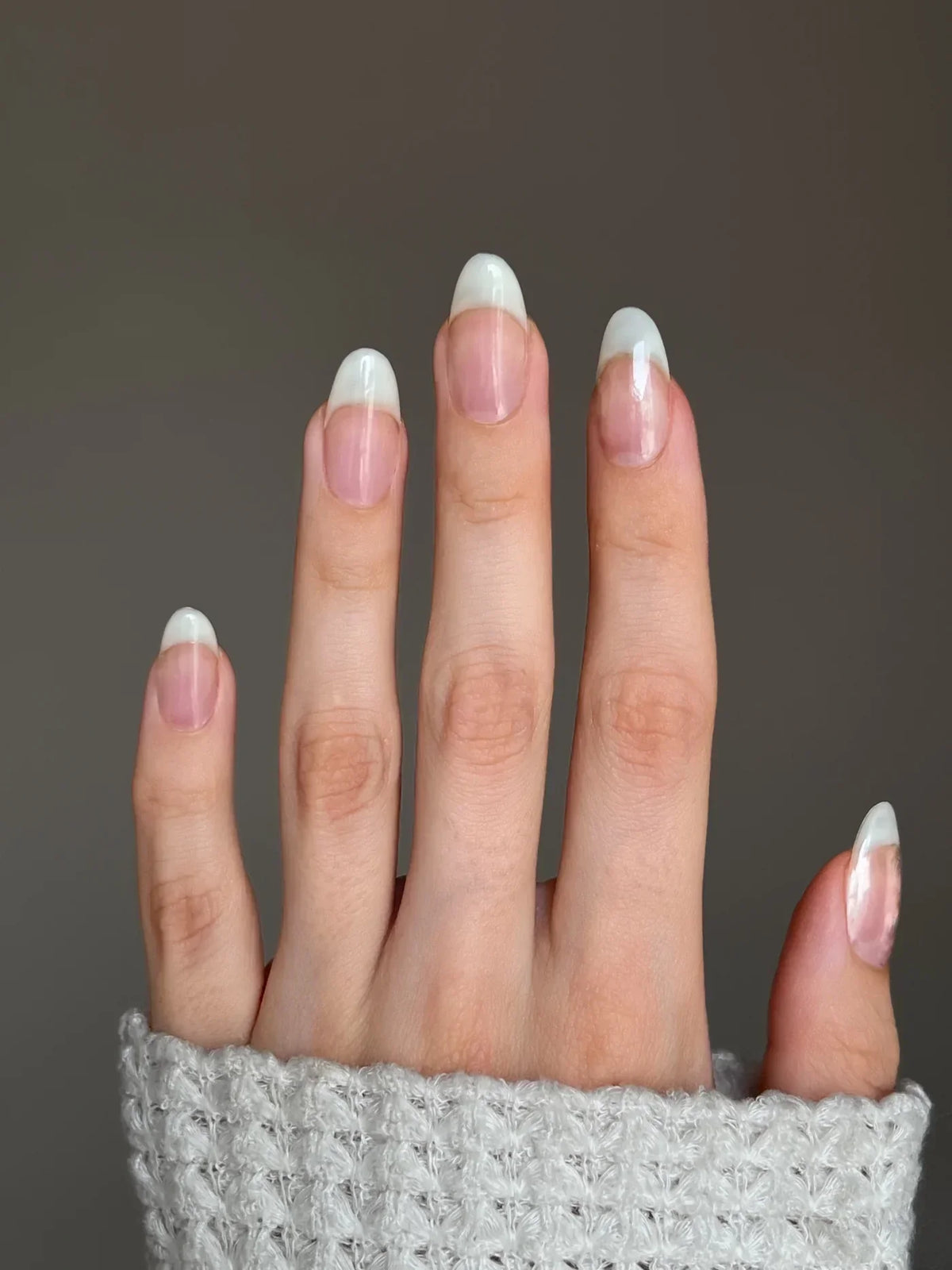 Een hand met netjes gelakte jelly nails met dipping powder en klassieke french tip roze nagelbedden en witte tanden