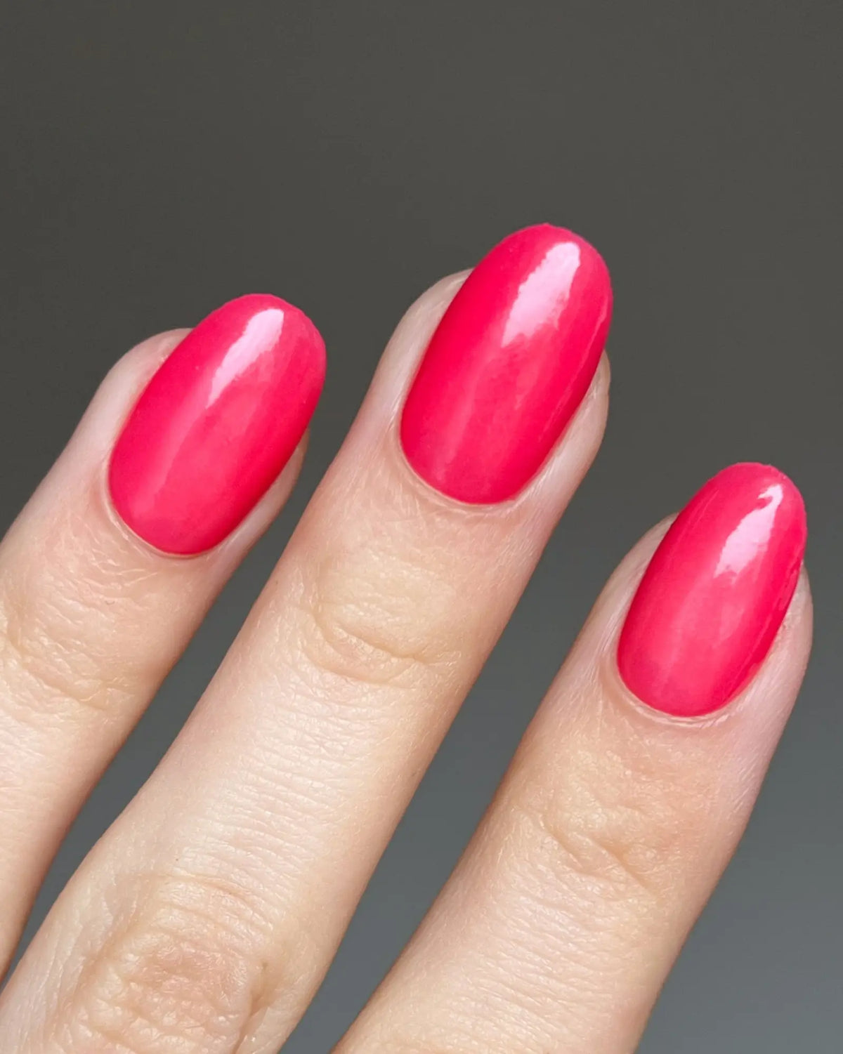 Vibrante fuchsia poeder nagellak met glanzende afwerking op net gemanicuurde ovale nagels