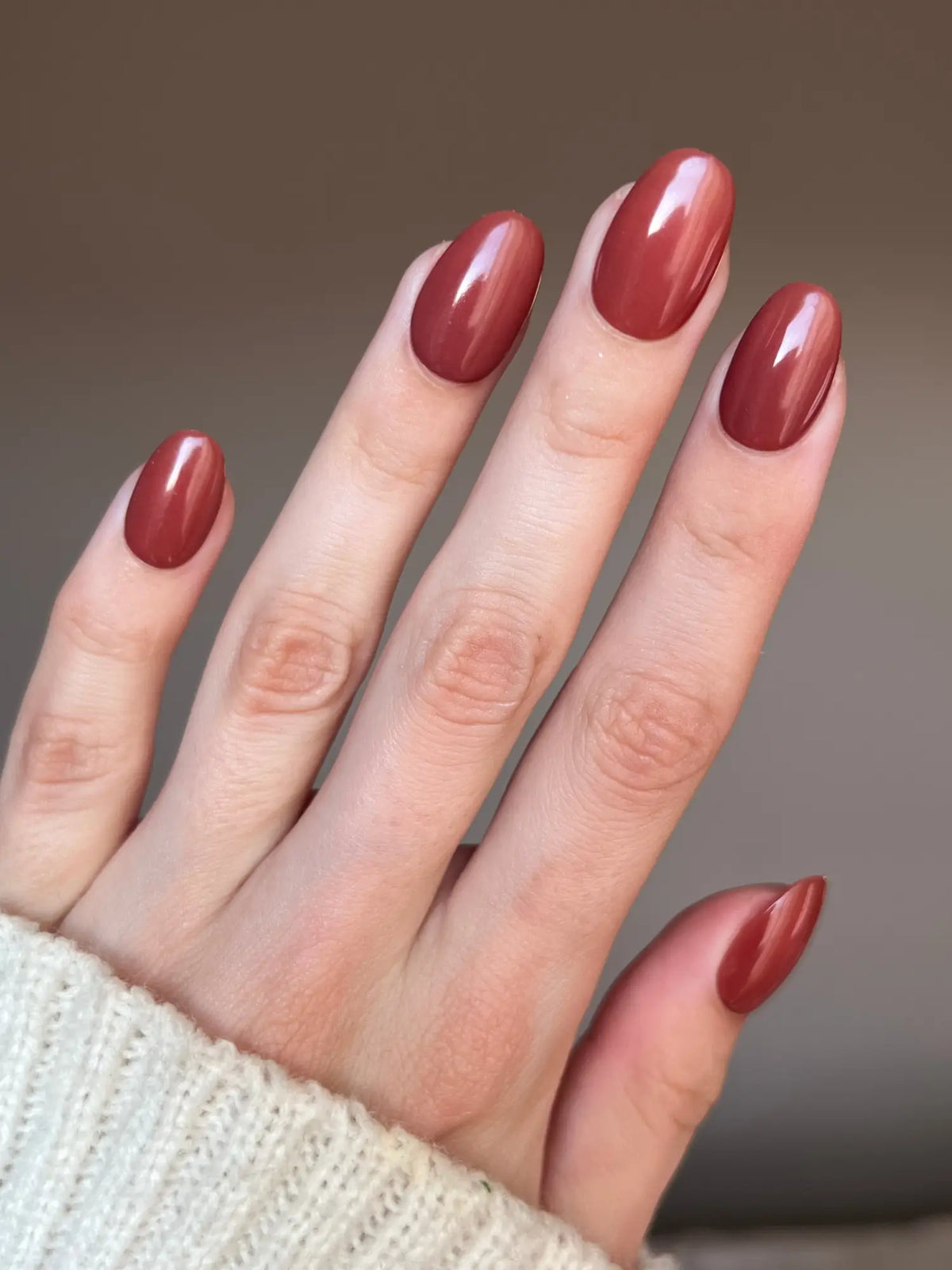Een hand met elegant geglazuurde nagels in een matte terracotta kleur na gebruik van dipping powder
