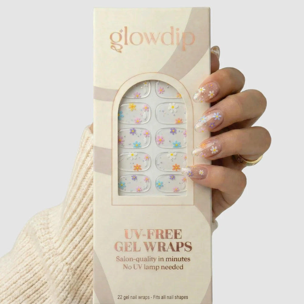 Een hand houdt een doos glowdip floral dream uv-free gel wraps met delicate bloemmotieven op transparante salonkwaliteit nagelwraps