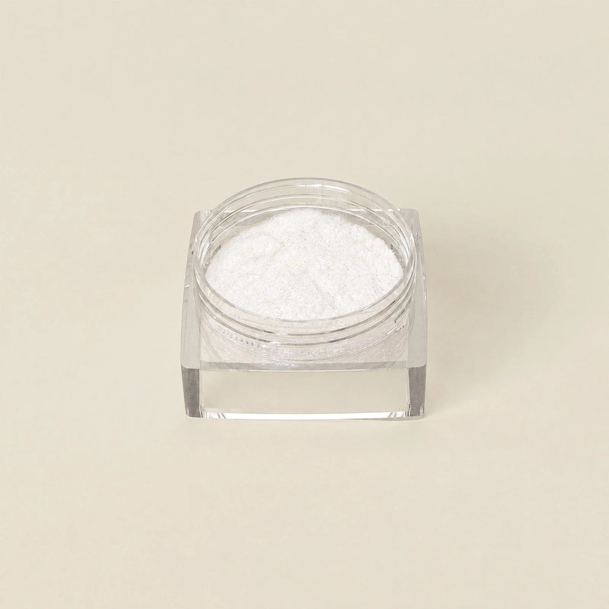 Een helder vierkant glazen potje gevuld met fijn wit poeder cosmic shift chrome powder