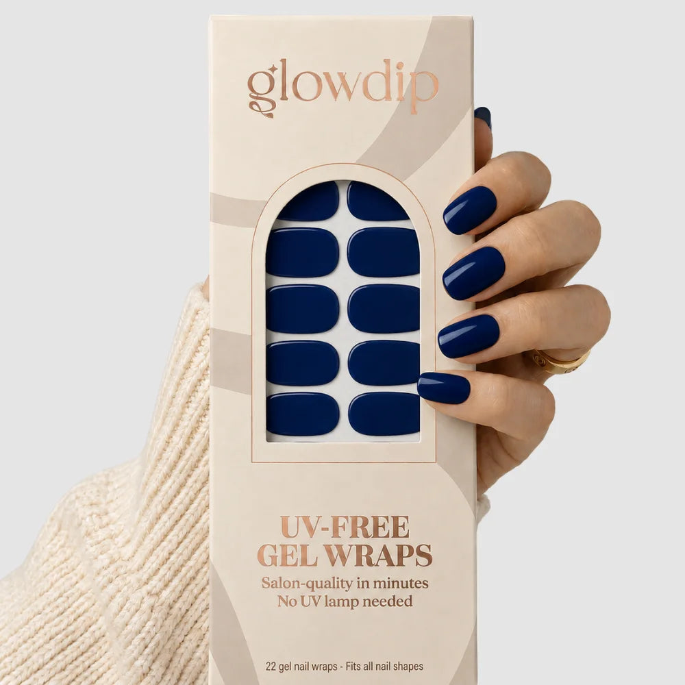 Een hand houdt een doos glowdip royal navy uv-free gel nagelwraps in diep marineblauw voor alle nagelvormen