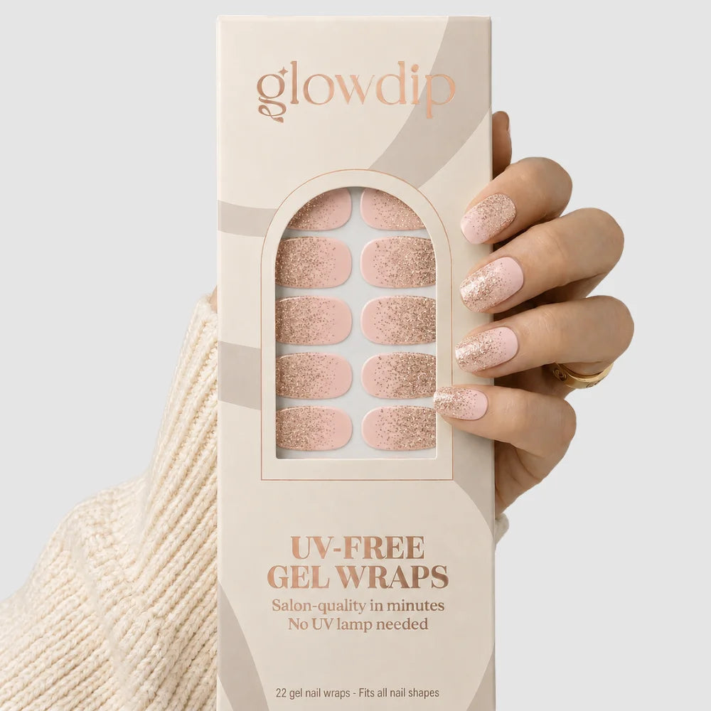 Een hand houdt een doos glowdip sparkle ombre uv-vrije gel wraps met roze en roségouden glitter nageldecoraties