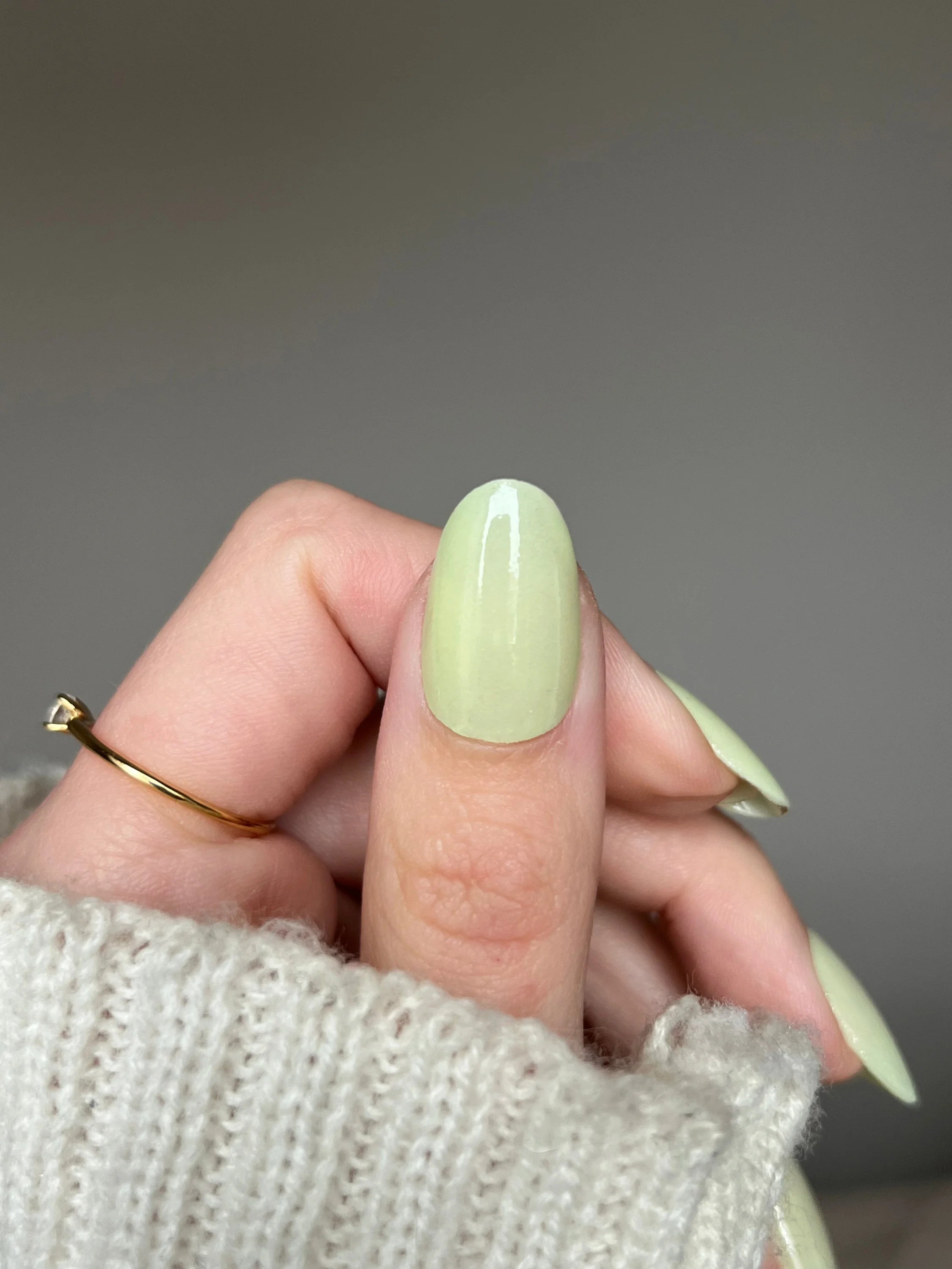 Een hand met lange, amandelvormige nagels gelakt met glanzende, bleekgroene vanilla dream dipping powder