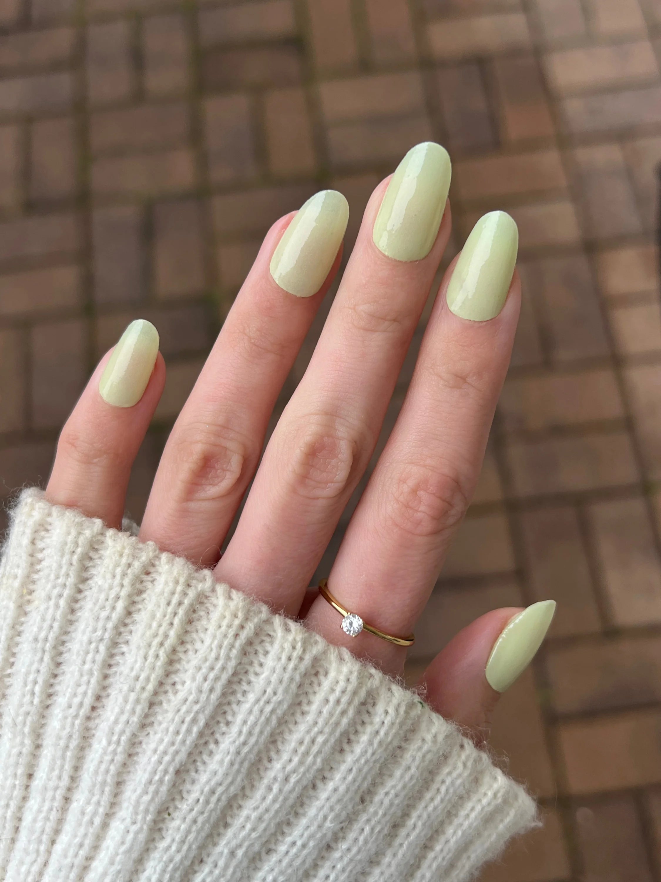 Hand met lange amandelvormige nagels gelakt in zachte matte pastelgroene kleur van vanilla dream dipping powder