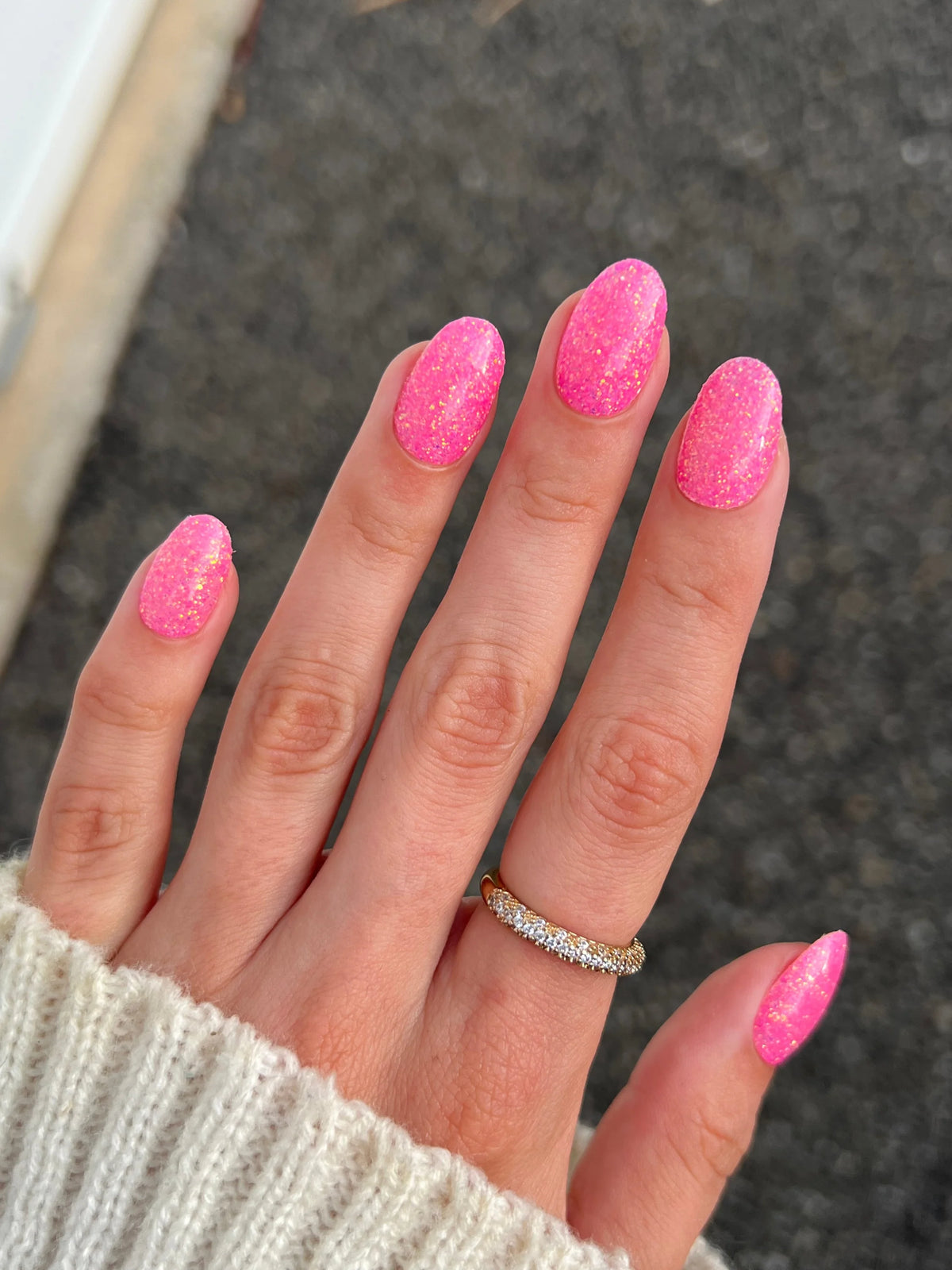 Hand met levendige roze glitter nagellak en gouden diamanten ring birthday bling dipping powder