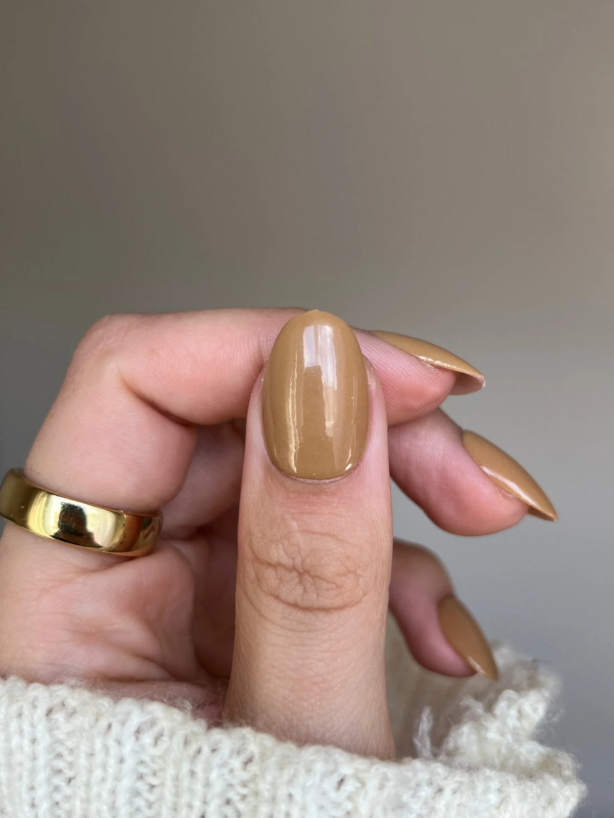 Hand met lange amandelvormige nagels gelakt met glanzende karamelkleurige golden drift dipping powder