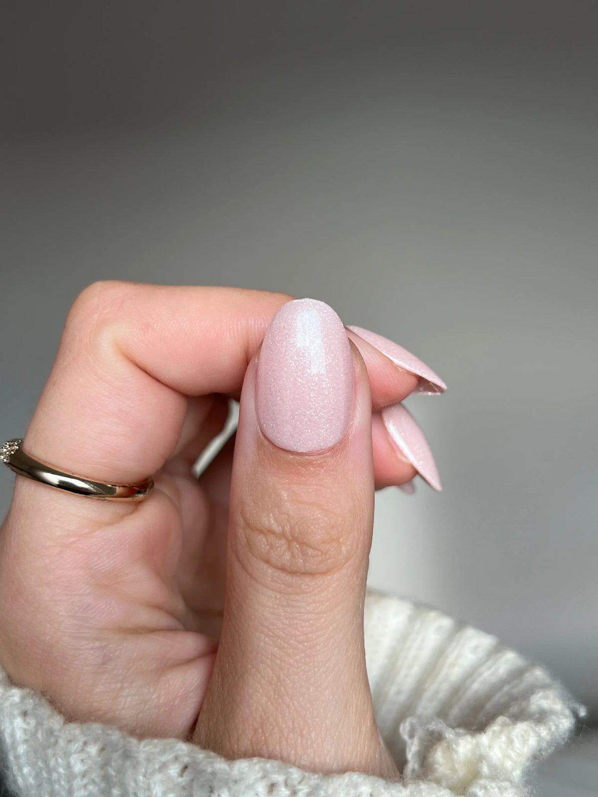 Een hand met elegant gemanicuurde nagels in zacht glanzende lichtroze silk veil dipping powder polish