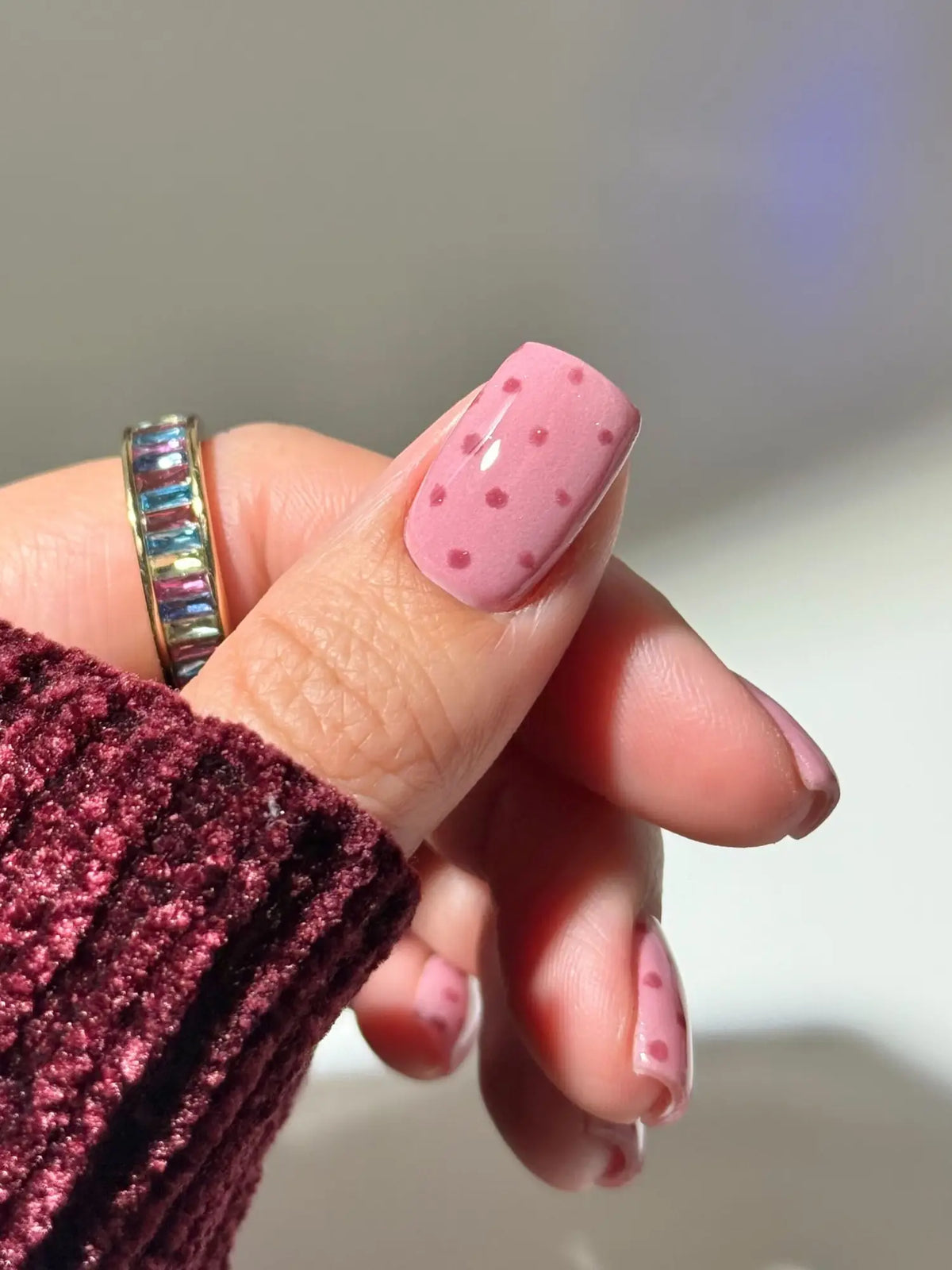 Pink nagellak met kleine donkerroze stippen bij een artikel over gelnagels versus dipping powder duurzaamheid