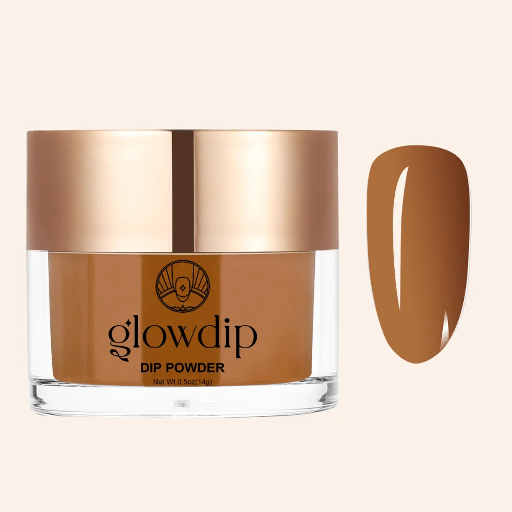 Een stijlvolle glazen pot met roségouden deksel bevat glowdip dip powder in een rijke karamelkleur amber clay