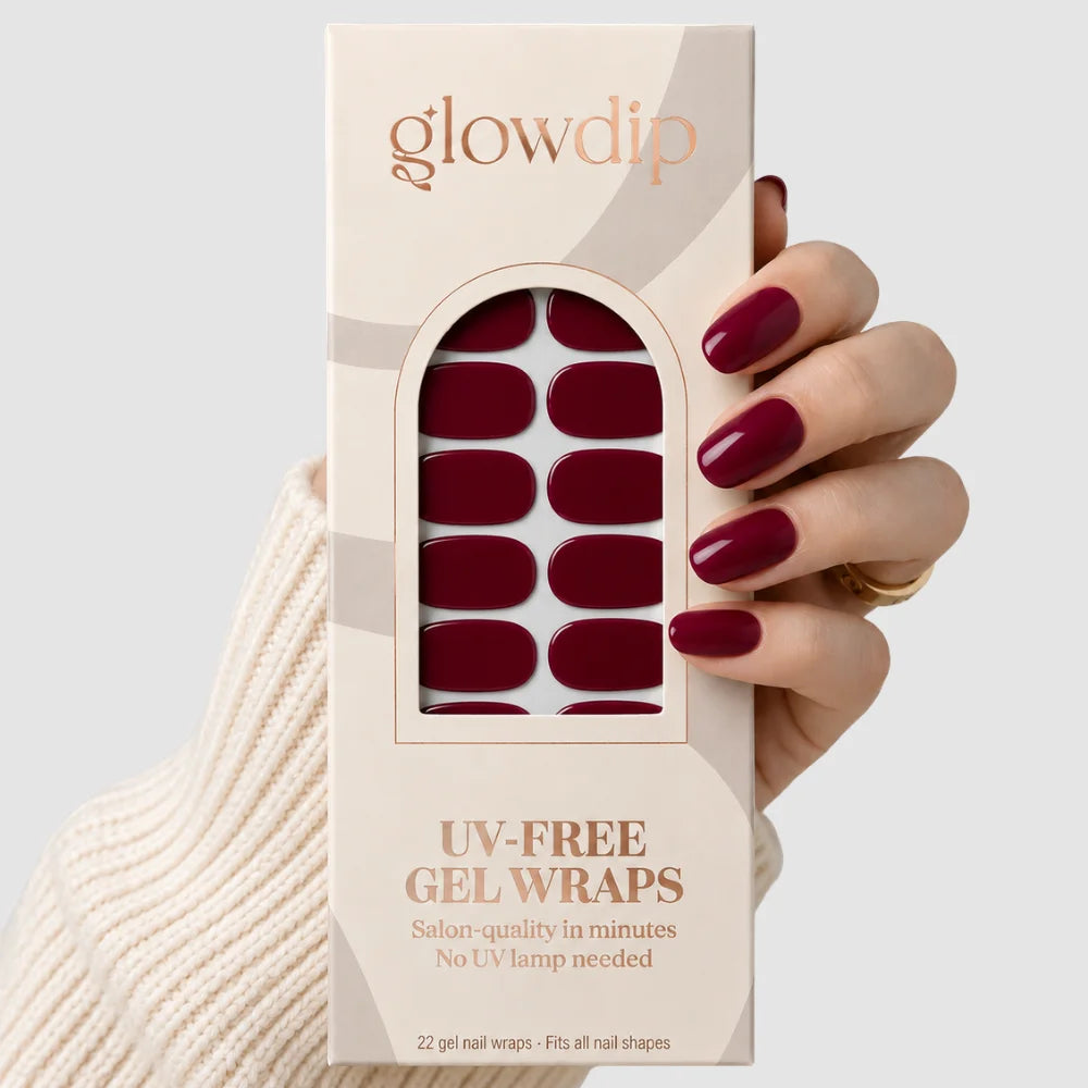 Een hand houdt een box glowdip uv-free gel wraps in bordeaux nachten kleur met 22 salonkwaliteit nagelwraps