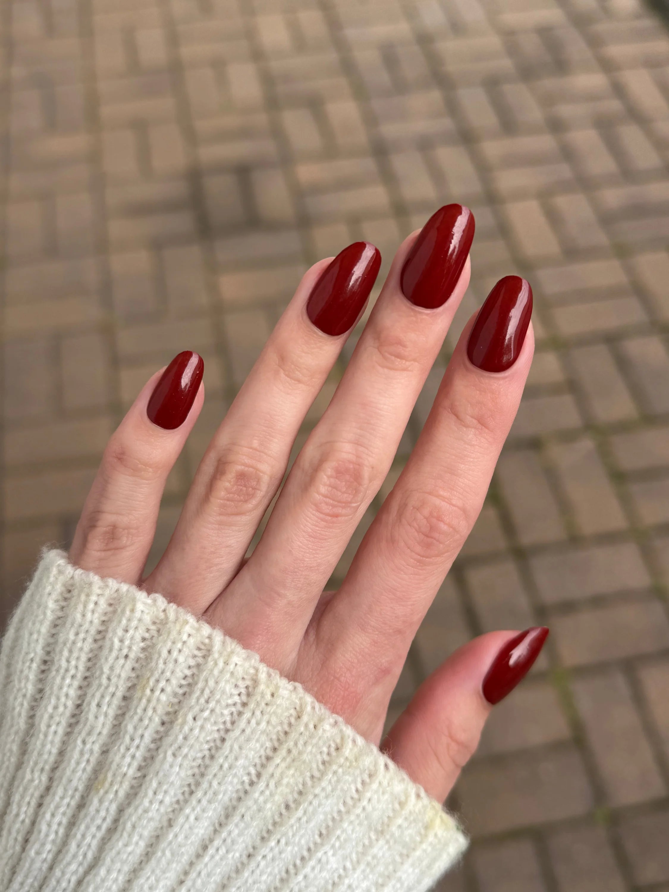 Dieprode glanzende bordeaux red dip powder op lange amandelvormige nagels