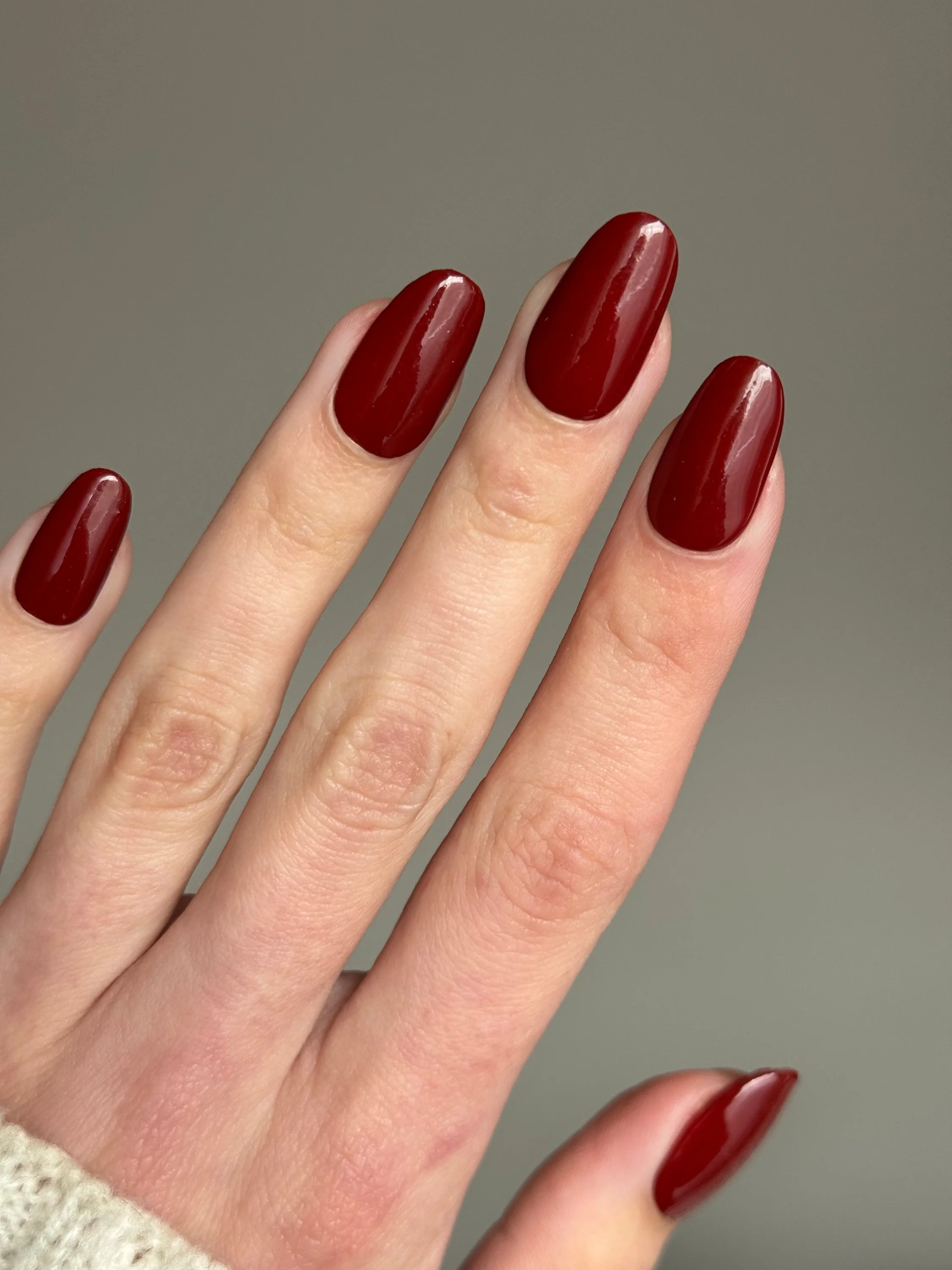 Dieprode glanzende dipping powder op netjes verzorgde nagels voor een duurzame bordeauxrode manicure