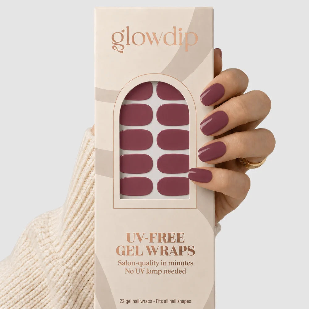 Een hand houdt een beige doos glowdip uv-free gel nagelwraps met diep mauve kleurige salonkwaliteit decals
