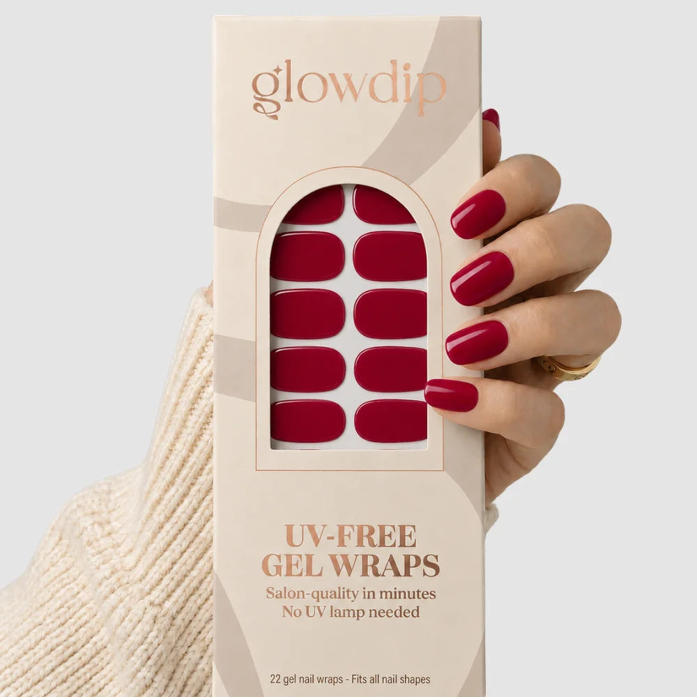 Een hand houdt een beige doos glowdip uv-free gel wraps met rode nageldecoraties van red affair