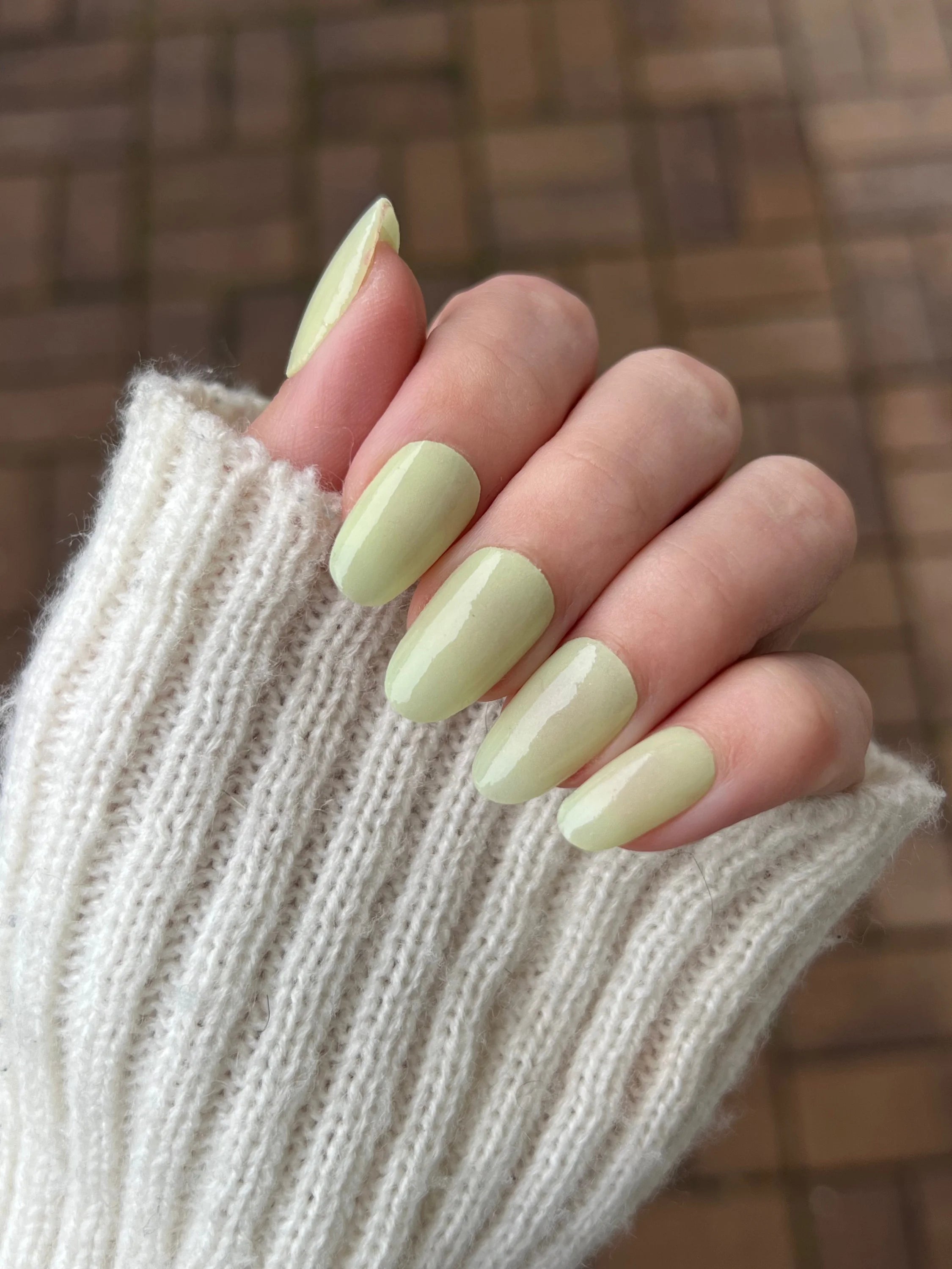 Hand met lange amandelvormige nagels in glanzende lichtgroene vanilla dream dipping powder lak