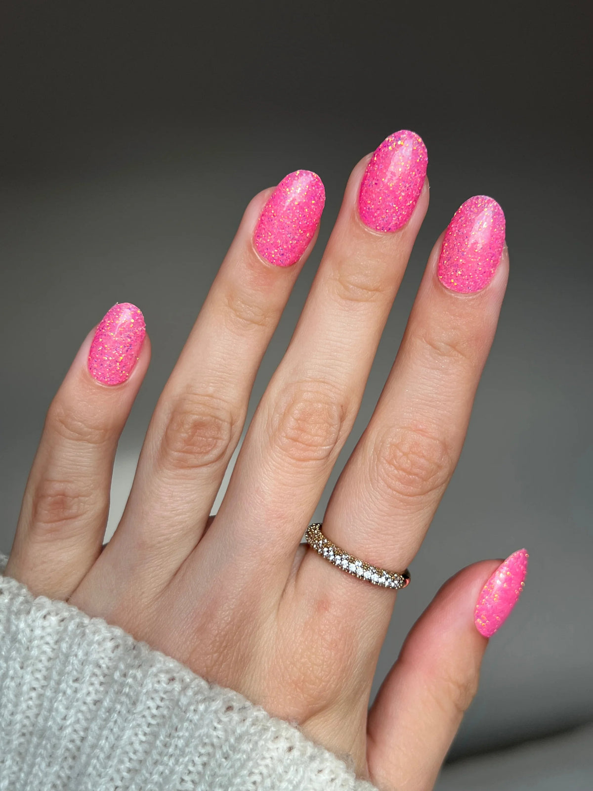 Hand met levendige roze glitter nagellak en delicate diamanten ring van birthday bling dipping powder product