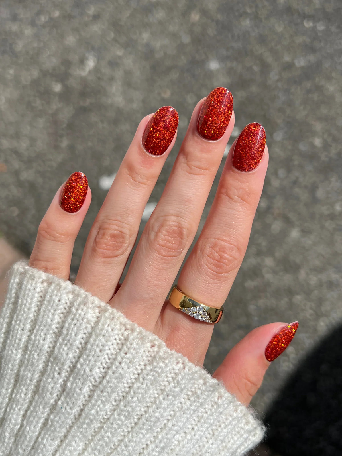 Hand met fel rood glitterend gelakte nagels en gouden ring in herfst bundel productfoto